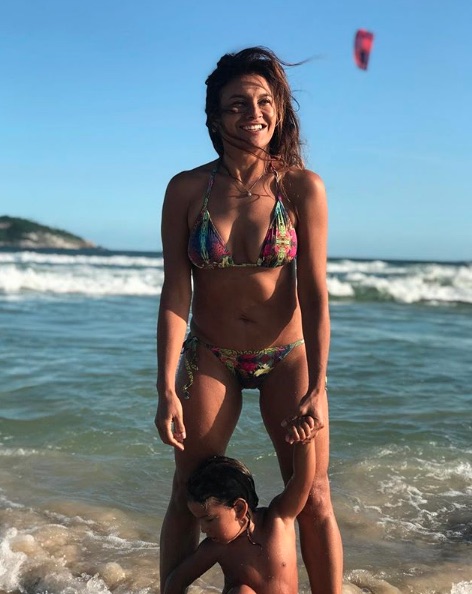 Em clique raro, Dira Paes posa de biquíni em dia de praia com o filho